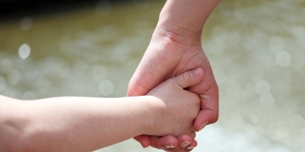 En voksen hånd der holder en barnehånd