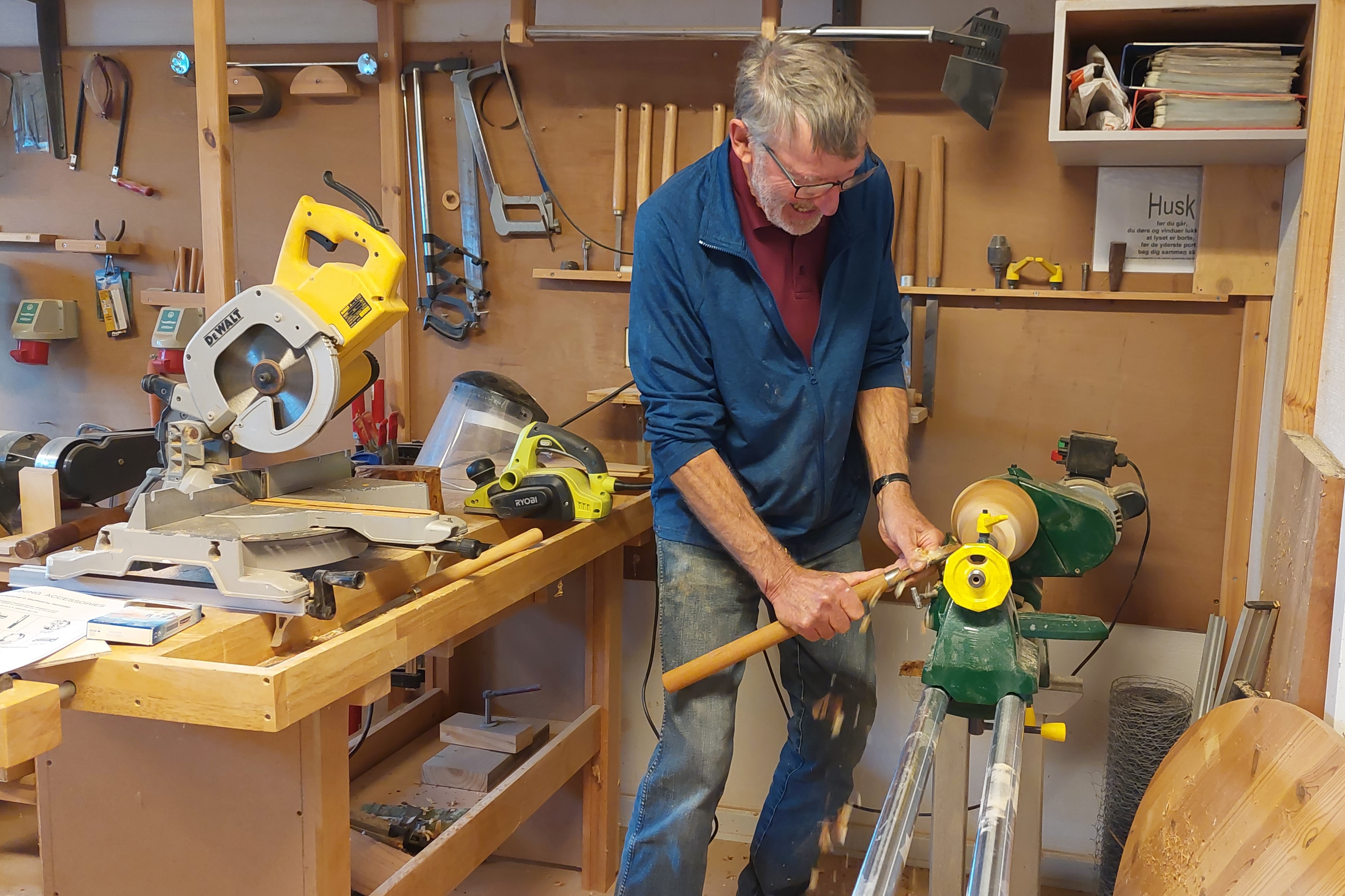 Mand står i værksted og skære træ