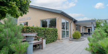 Billede af indgangen til Birkelund. Grønne træer i forgrunden
