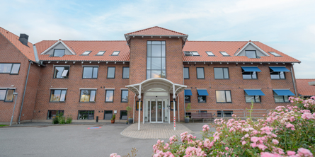 Kirkedal indgangsparti med lyserøde blomster i forgrunden