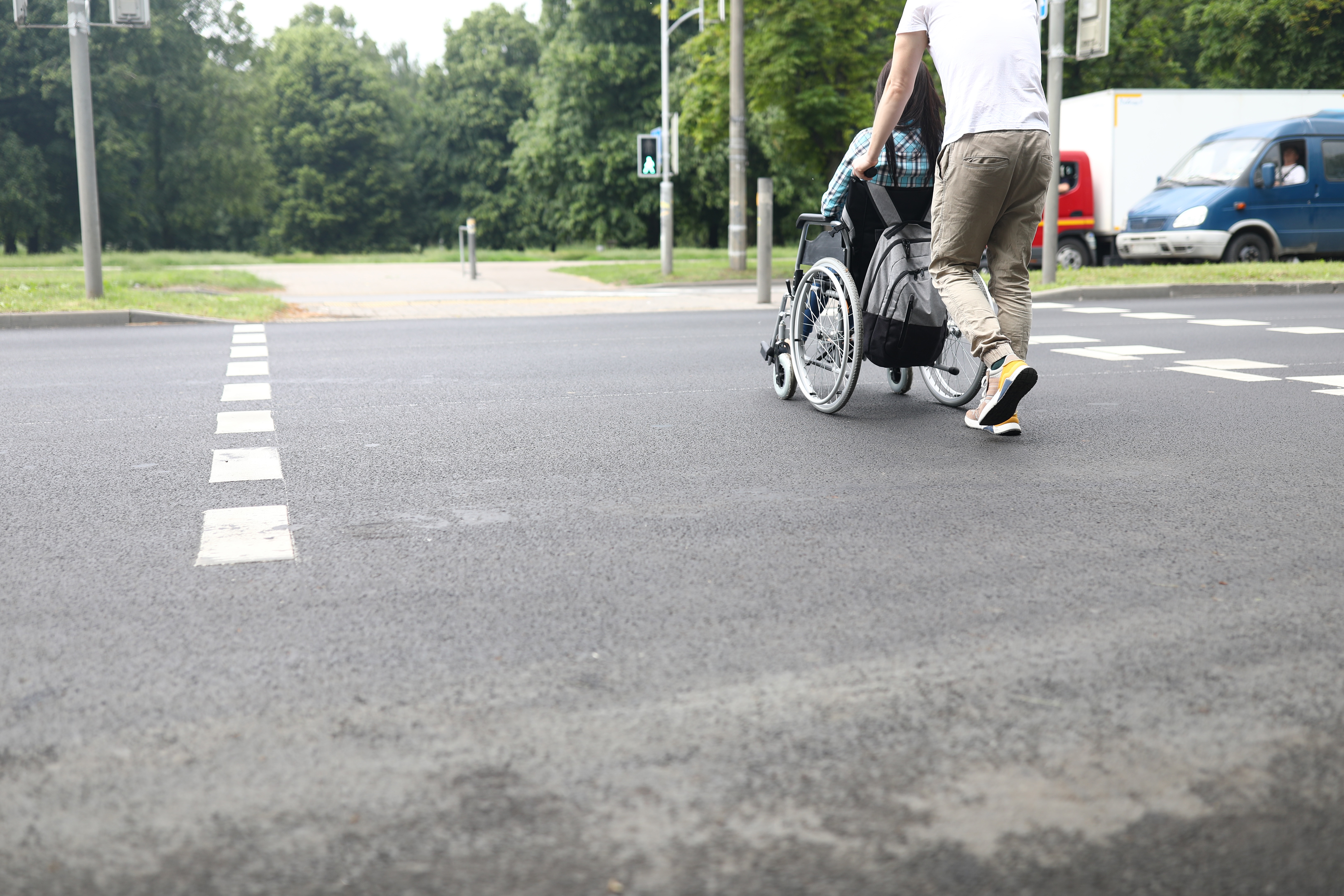 Kørestolsbruger der bliver hjulpet over fodgængerfelt